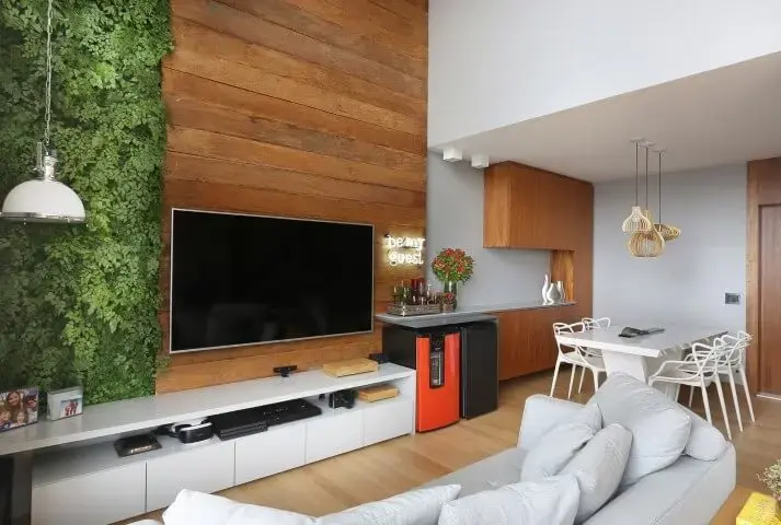 Sala de estar com jardim vertical ao lado da parede revestida de madeira Projeto de Estúdio AE