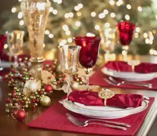 Tons de vermelho no lugar americano, guardanapo de pano e taças na mesa de ceia de natal Foto de Splender