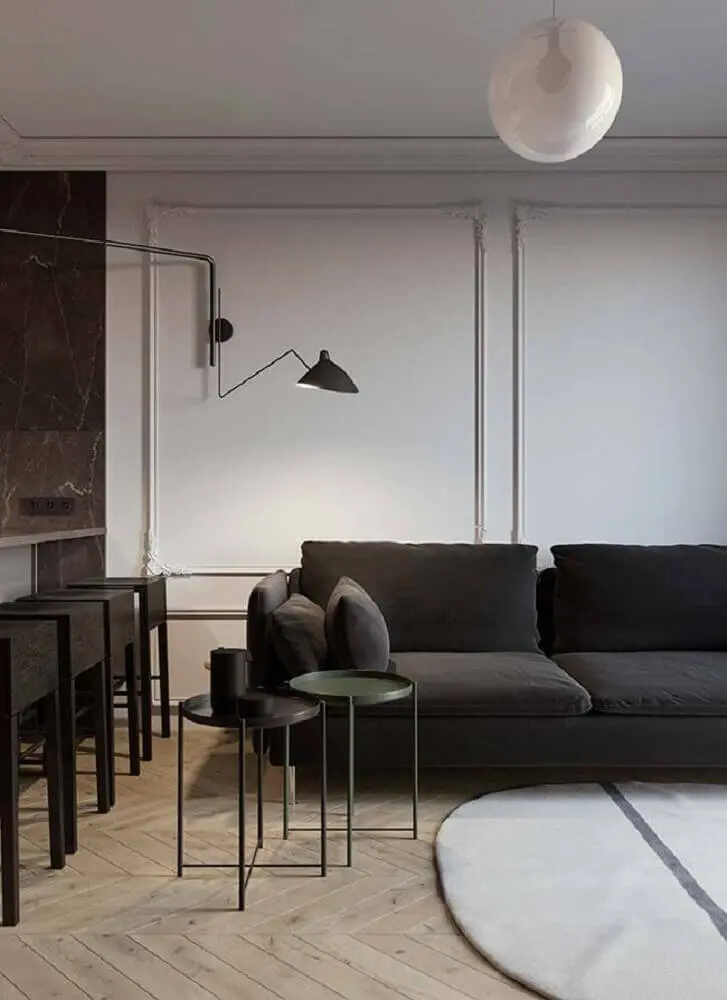 ambiente moderno com boiserie sofá preto e luminária de parede Foto Pinterest