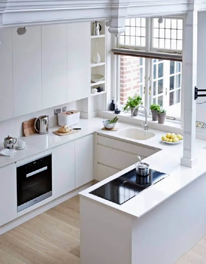Cozinha planejada com amplas janelas e armários brancos