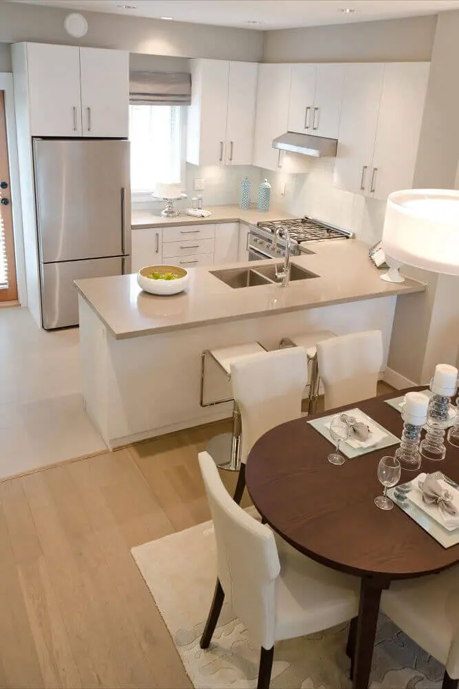decoração clean para cozinha integrada com sala jantar com cadeiras brancas e mesa de madeira Foto Mi casa revista