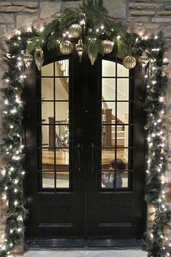 varanda decorada com luzes de natal e enfeites dourados Foto Divian Arts