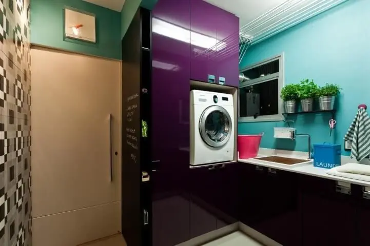 Área de serviço planejada com armário roxo e máquina de lavar encaixada Projeto de Juliana Pippi