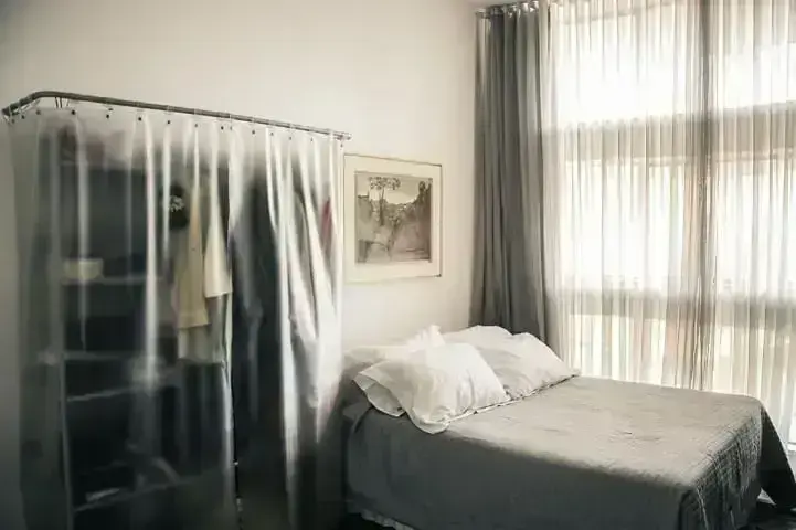 Apartamento pequeno decorado com quarto com arara protegida por cortina plástica Projeto de Casa Aberta