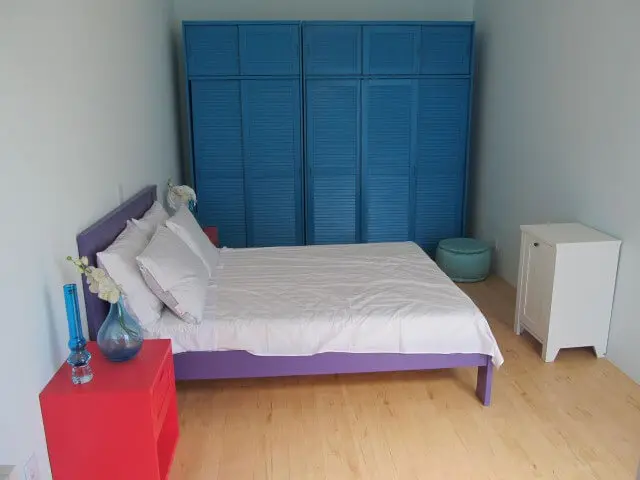 Armário de quarto azul com cama rosa e criado-mudo vermelho Projeto de Brunete Fraccaroli