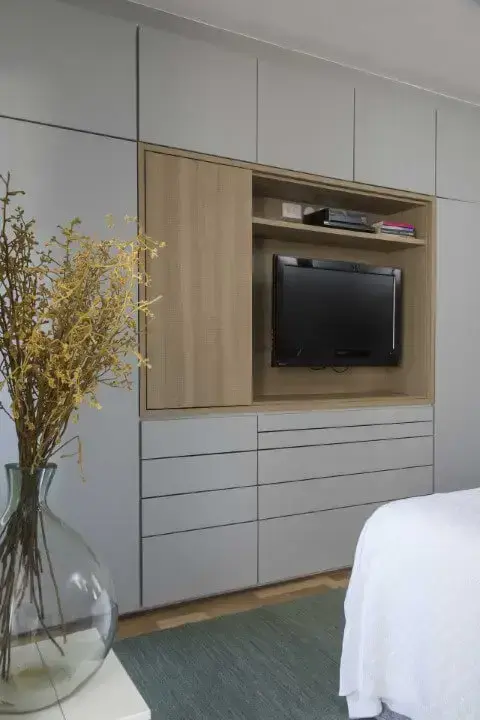 Armário de quarto de casal cinza com painel de TV embutida Projeto de Ana Yoshida