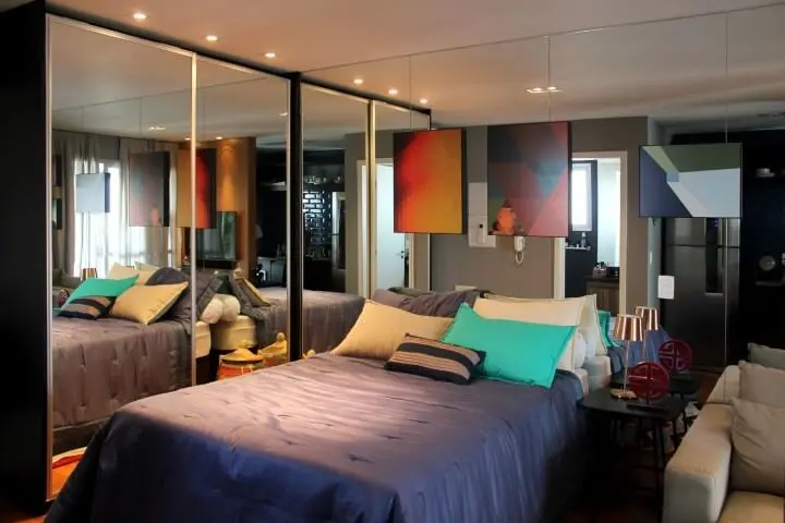 Armário de quarto de casal com portas e paredes espelhadas Projeto de Zark Studio