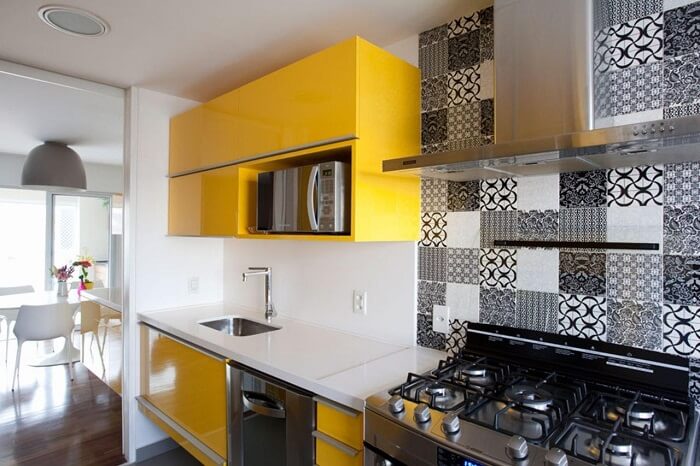 Cozinha com armário amarelo e ladrilho hidráulico