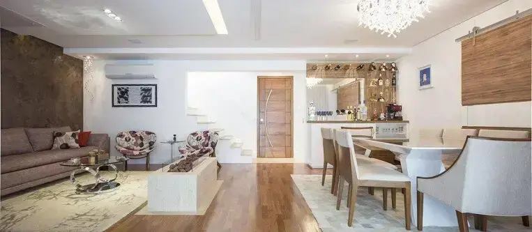 O piso de madeira compõe o revestimento tanto da sala de estar quanto da sala de jantar