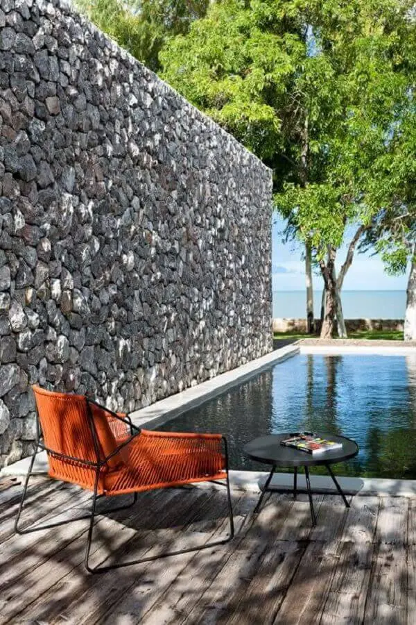 O revestimento de parede externa da área da piscina foi feita com pedra natural cinza. Fonte: Pinterest