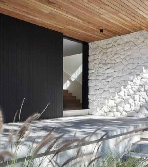 O revestimento de parede externa feita com pedra madeira branca se harmoniza com o forro de madeira. Fonte: Pinterest