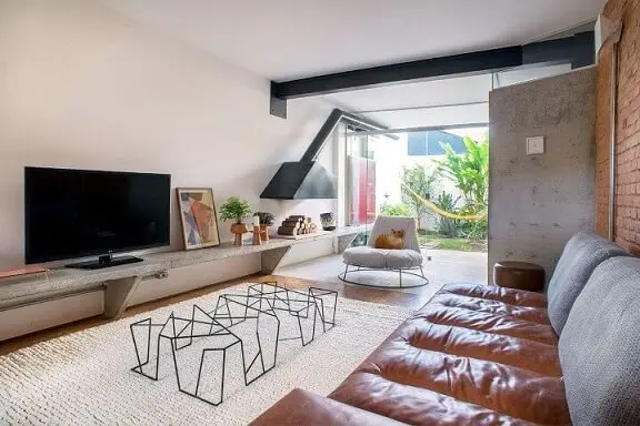 Sala de TV com sofá de couro e almofadas de crochê Projeto de Odvo Arquitetura