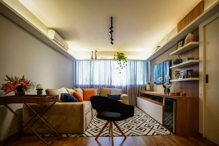 Sala de TV com sofá em L bege e painel de TV de madeira Projeto de Gabriela Toledo