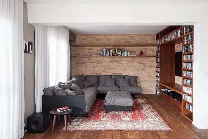 Sala de TV com sofá em L cinza com puff central combinando Projeto de Korman Arquitetos
