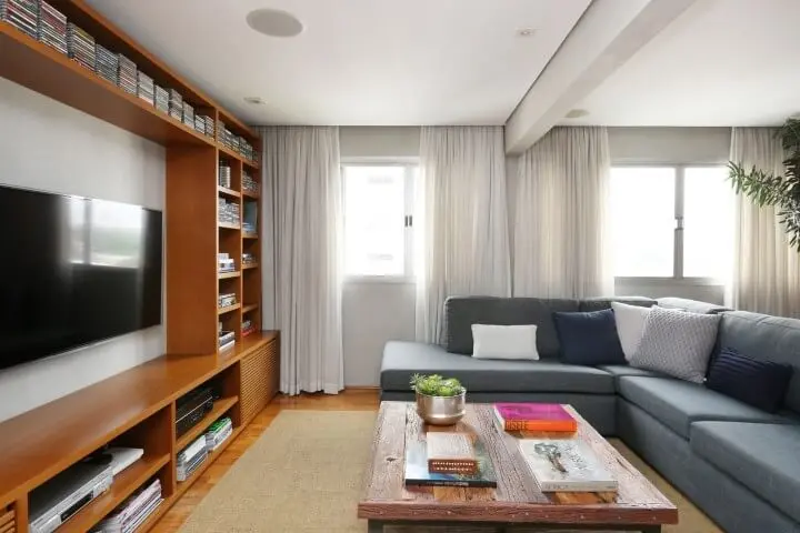 Sala de TV com sofá em L cinza e estante de madeira Projeto de Oliveira Arquitetura