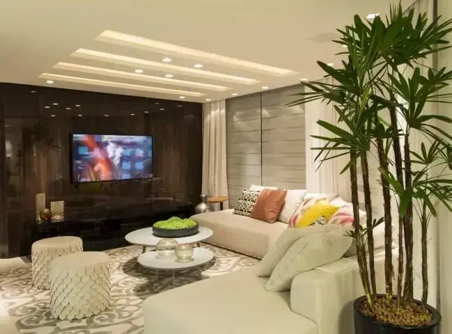 Sala de TV com sofá em L combinando com os puffs Projeto de Anna e Anderson