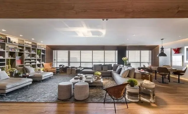Sala de estar amplo com sofá em L cinza combinando com o tapete Projeto de Triplex Arquitetura