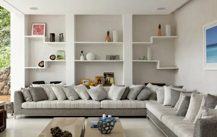 Sala de estar clean com sofá em L branco e cinza com almofadas combinando Projeto de Sandra Picciotto