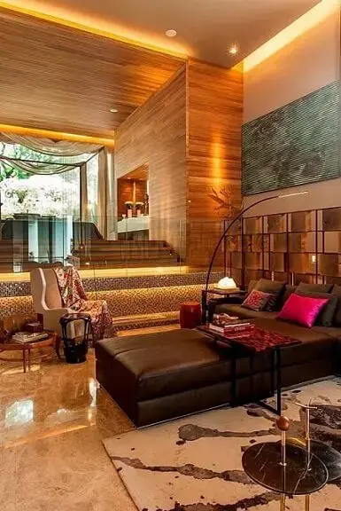 Sala de estar com decoração aconchegante e sofá de couro marrom escuro com chaise Projeto de Denise Barretto