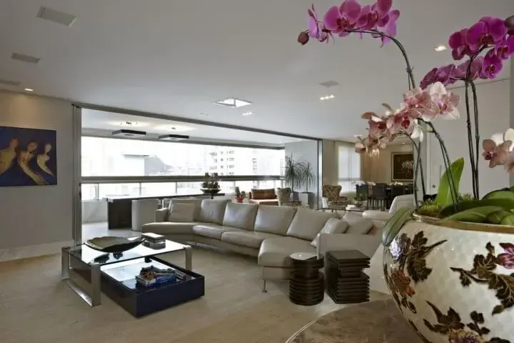 Sala de estar com decoração em tons claros com sofá de couro creme Projeto de Gislene Lopes