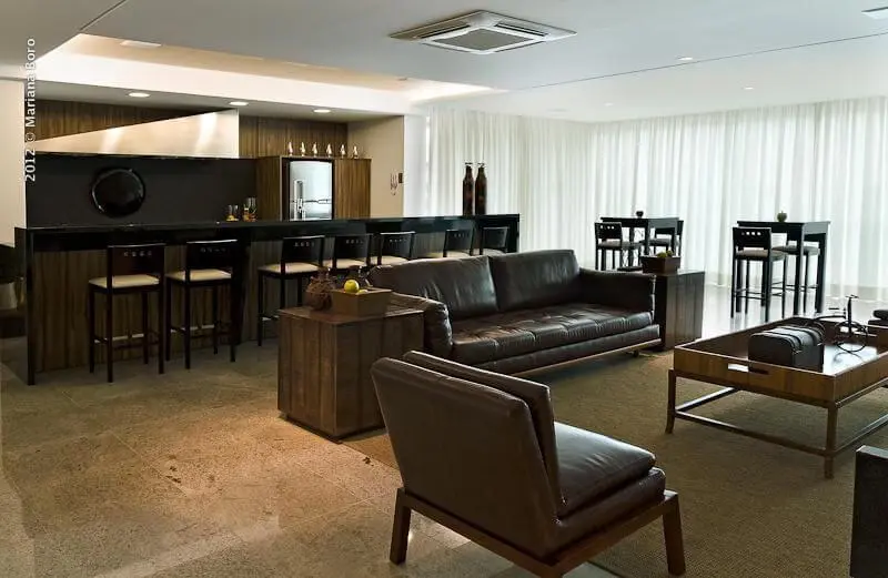 Sala de estar com sofá de couro e móveis de madeira Projeto de Rico Mendonça
