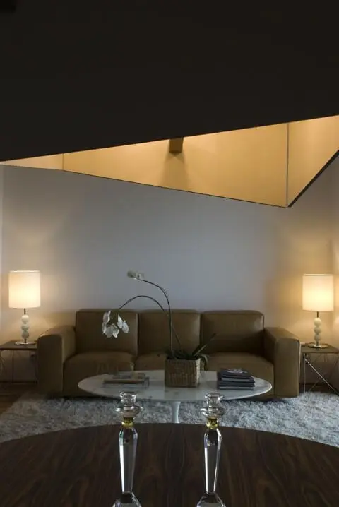 Sala de estar com sofá de couro marrom claro com abajures dos lados Projeto de Arq Donini