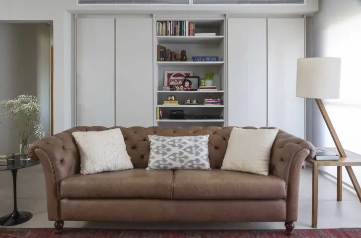 Sala de estar com sofá de couro marrom claro e pés redondos Projeto de Ana Yoshida
