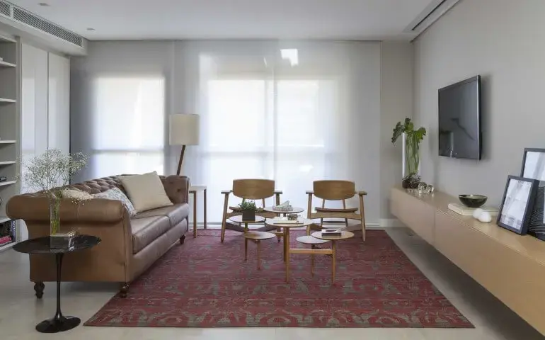 Sala de estar com sofá de couro marrom claro e tapete estampado Projeti de Ana Yoshida