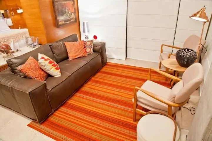 Sala de estar com sofá de couro marrom com almofadas combinando com o tapete Projeto de Rico Mendonça