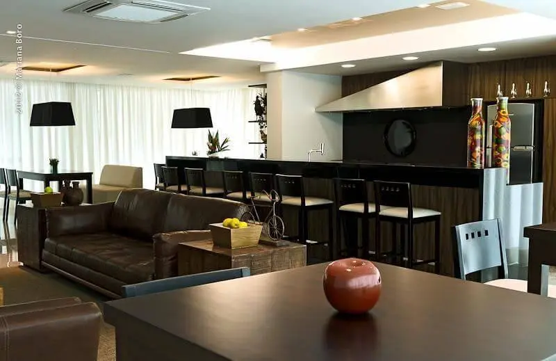 Sala de estar com sofá de couro marrom com cozinha integrada Projeto de Rico Mendonça