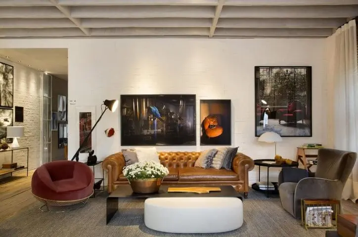 Sala de estar com sofá de couro marrom com poltronas de veludo Projeto de Paola Ribeiro