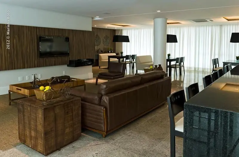 Sala de estar com sofá de couro marrom combinando com os tons de marrom da decoração Projeto de Rico Mendonca