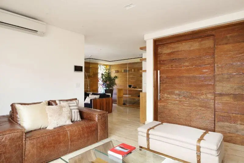 Sala de estar com sofá de couro marrom e almofadas claras Projeto de Studio BR