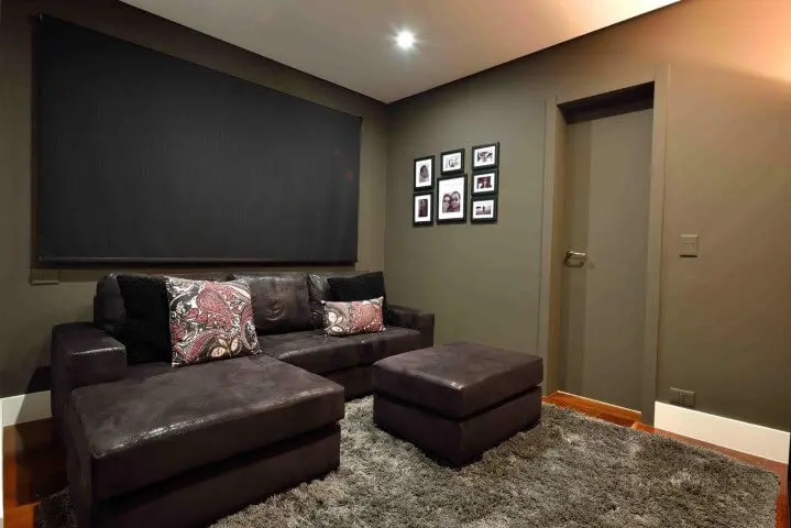 Sala de estar com sofá de couro marrom escuro e tapete felpudo Projeto de Rafael Guimarães
