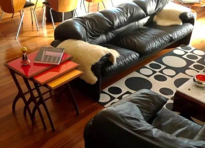 Sala de estar com sofá de couro preto com mantas de pele Projeto de Desmobilia