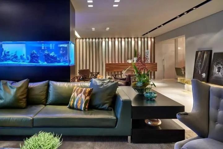 Sala de estar com sofá de couro verde e aquário Projeto de Gislene Lopes