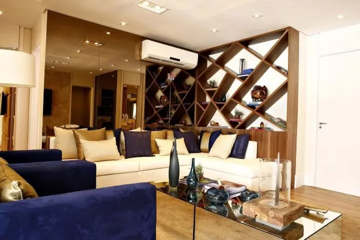 Sala de estar com sofá em L branco com estante de madeira embutida Projeto de Marel
