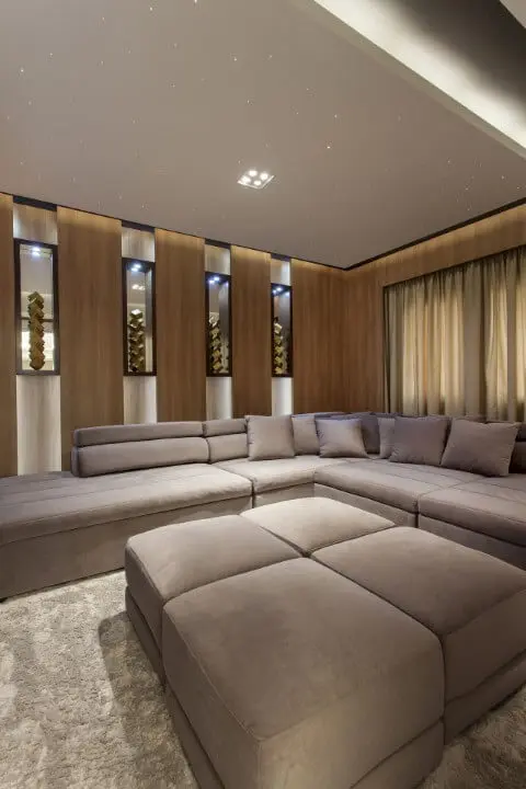 Sala de estar com sofá em L cinza e puffs grandes no centro Projeto de Iara Kilaris