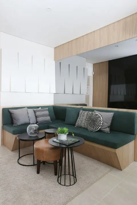 Sala de estar com sofá em L com estrutura de madeira e almofadas verdes Projeto de Anna Maria Parisi