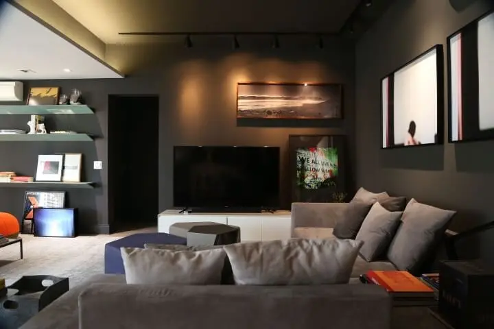 Sala de estar preta com sofá em L pequeno e almofadas cinzas Projeto de Triart Arquitetura