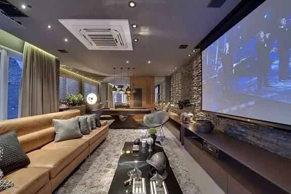 Sala de estar sofisticada com sofá de couro caramelo claro e parede canjiquinha Projeto de Carla Felippi