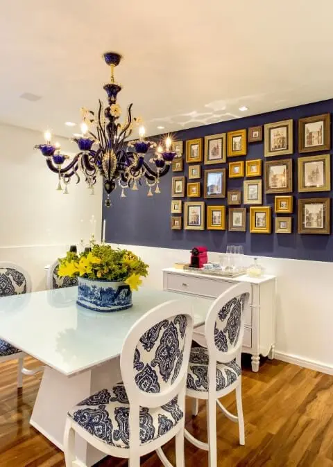 Sala de jantar com parede azul e várias molduras para quadros combinando entre si e com a decoração Projeto de Milla Holtz