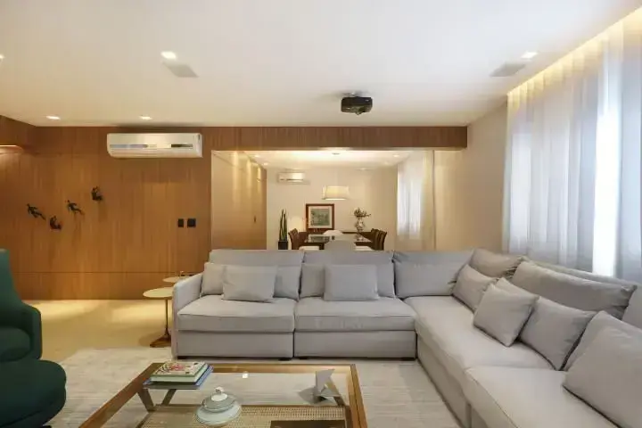Sala integrada com sofá em L claro dividindo o ambiente de estar do ambiente de jantar Projeto de Start Arquitetura