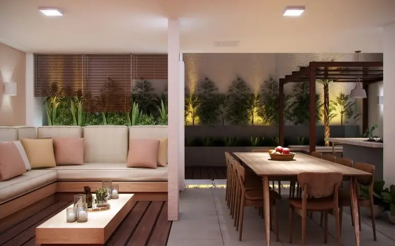 Varanda gourmet com sofá em L e almofadas em cores pastel Projeto de Amora Arquitetura