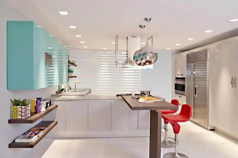 cozinha azul turquesa e branca com armários planejados e banquetas vermelhas Foto The Holk