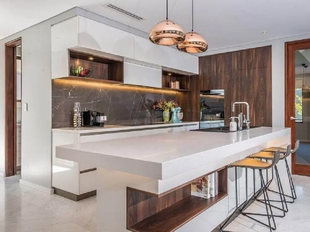 cozinha moderna decorada com pendentes sobre bancada nanoglass e iluminação embutida em armário aéreo Foto Letícia Borges