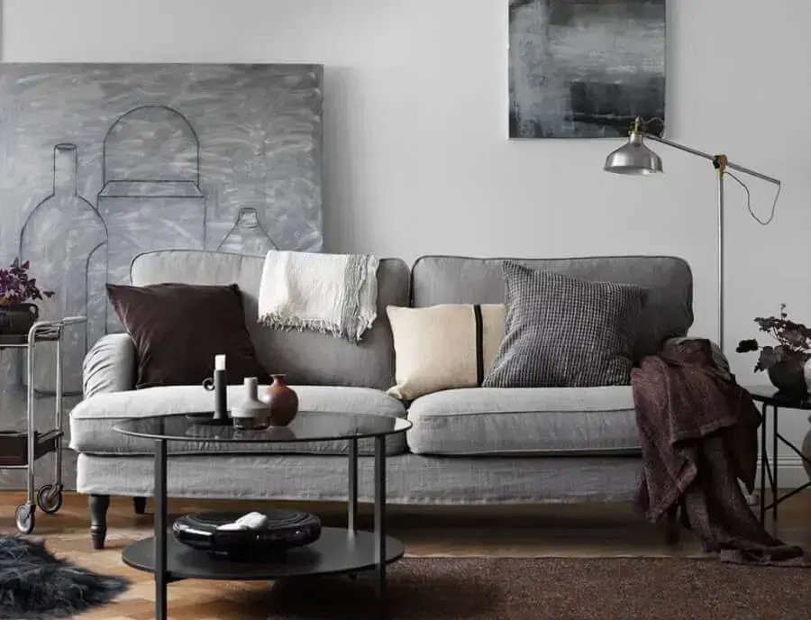 decoração sala moderna em tons de cinza com grande quadro mesa de centro redonda e manta para sofá Foto IProperty