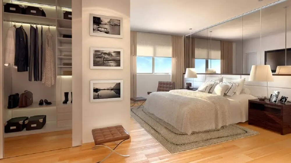 modelo de quarto de casal com closet pequeno decorado com piso de madeira e parede espelhada Foto Estéfany Furtado