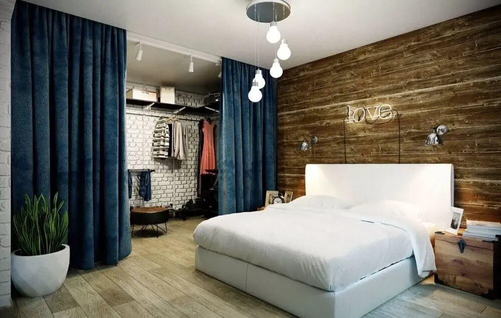 quarto de casal com closet com divisória de cortina azul e parede de tijolinho branco Foto Yandex