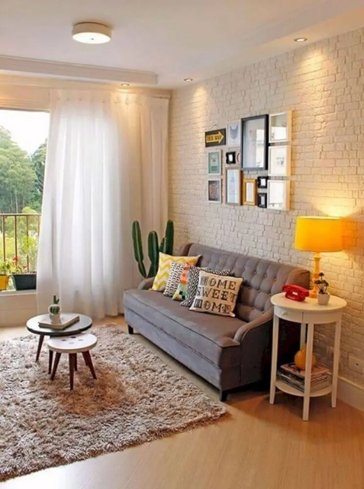 sofá cinza para sala pequena decorada com parede de tijolinho e vaso de cacto Foto Futurist Architecture
